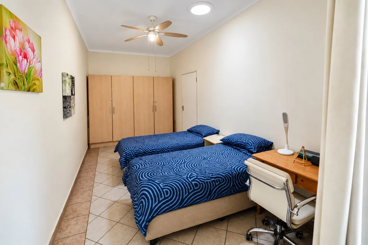 Bedroom with blue bedding, bedside table and fitted cupboards